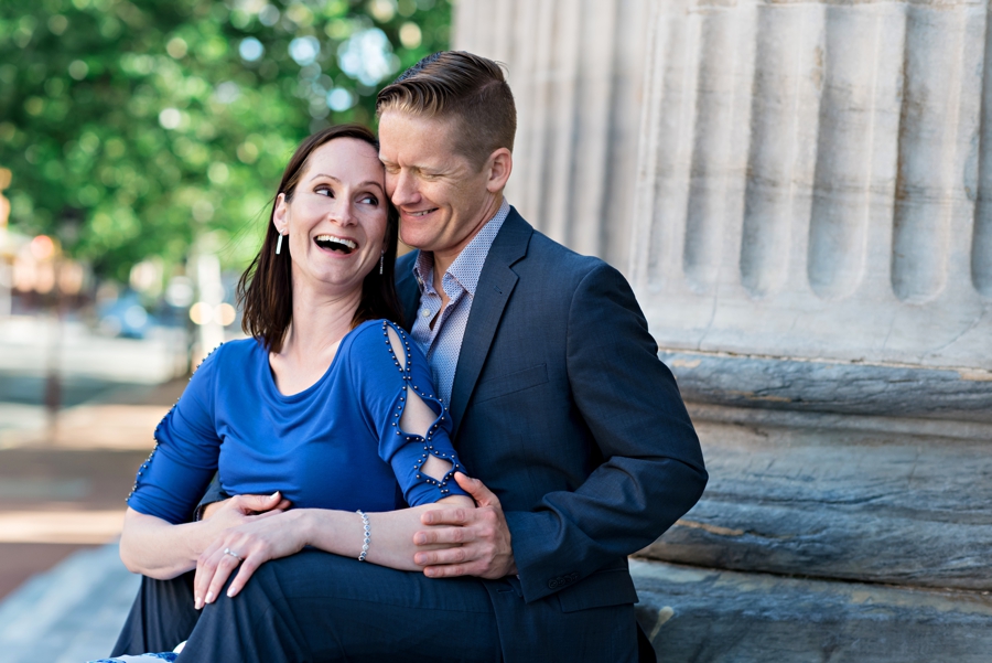A man makes his fiance laugh while they sit on the steps of a historic philadelphia building.